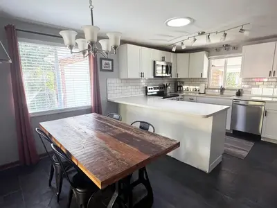a kitchen with a wooden table with chairs and a counter at Crown Hill Gem - Hot Tub, Yard, Parking in Lakewood