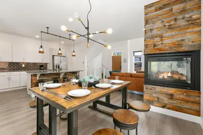 a kitchen and living room with a table and a fireplace at The Cycle Haus Rooftop Deck with Hot Tub and Views in Fort Collins