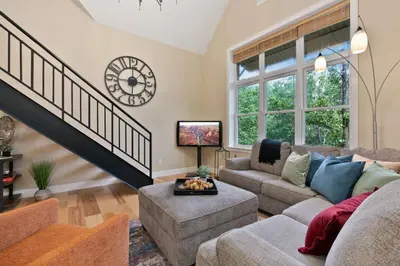 a living room with a couch and a clock on the wall at Royal Perch - Chic Old Town Loft with King Suite in Fort Collins