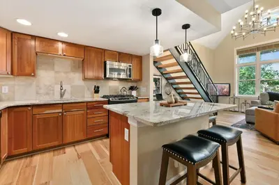 a kitchen with wooden cabinets and a kitchen island with bar stools at Royal Perch - Chic Old Town Loft with King Suite in Fort Collins