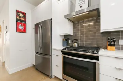 a kitchen with white cabinets and a stainless steel refrigerator at Elegant Mountain Haven - King Bed and Fireplaces in Fort Collins
