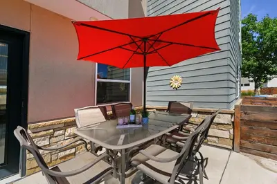 a table and chairs with a red umbrella on a patio at Elegant Mountain Haven - King Bed and Fireplaces in Fort Collins