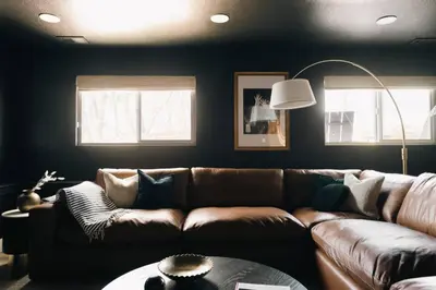a living room with a brown couch and two windows at House of Noir Elan Stunning 6BR Designer Retreat in Arvada