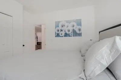 a white bedroom with a bed and a mirror at 16 Mi to Dtwn Denver Modern Apt with Patio in Denver