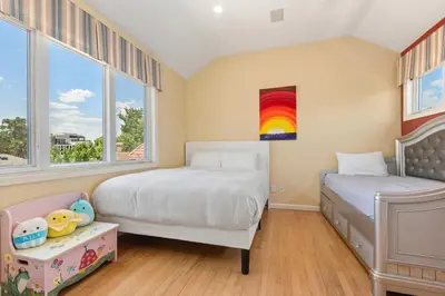 a bedroom with two beds and a rainbow painting on the wall at Heart of Cherry Creek Group Retreat Hot Tub in Denver