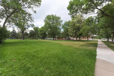 a park with green grass and trees and a sidewalk at Chic Lower-Level Stay - Prime Walkable Locale in Denver