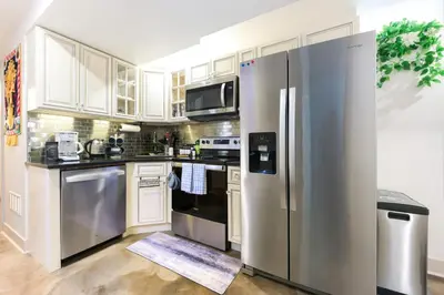 a kitchen with white cabinets and a stainless steel refrigerator at Chic Lower-Level Stay - Prime Walkable Locale in Denver