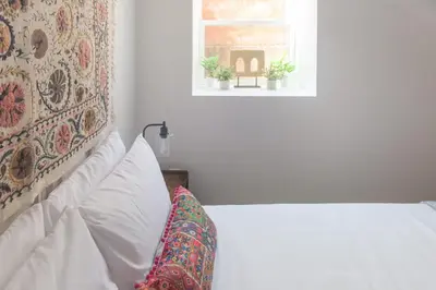 a white bed with a pillow and a window at Chic Lower-Level Stay - Prime Walkable Locale in Denver