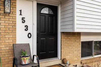 a black front door of a house with a chair at Spacious and Comfy Close to Everything Backyard in Longmont