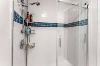 a bathroom with a shower with blue and white tiles at Spacious and Comfy Close to Everything Backyard in Longmont