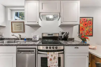 a kitchen with white cabinets and a stove top oven at Modern Downtown Oasis Sunny Garden King Beds in Longmont