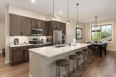 a kitchen with wooden cabinets and a large island with bar stools at Downtown Flat condo in Winter Park
