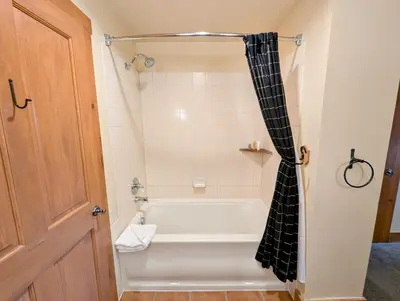 a bathroom with a bath tub with a black and white shower curtain at Expedition Station 8634 by SummitCove Lodging in Keystone