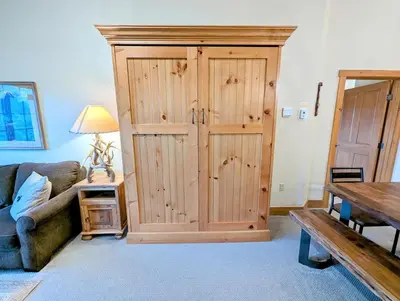a large wooden cabinet in a living room with a couch at Expedition Station 8634 by SummitCove Lodging in Keystone