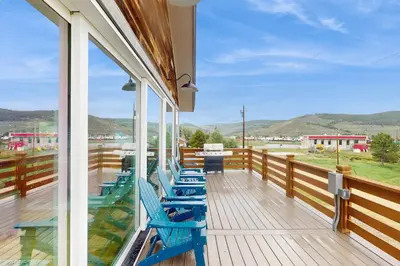a deck with blue chairs and a table on a balcony at Lance's Adventure Lodge in Tabernash