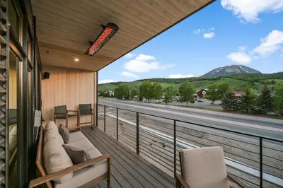 a balcony with a couch and a view of a road at 4-Season Modern Mountain Penthouse with Private Hot Tub & Scenic Views in Silverthorne