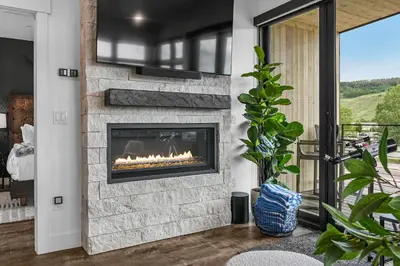 a fireplace in a living room with a view at 4-Season Modern Mountain Penthouse with Private Hot Tub & Scenic Views in Silverthorne