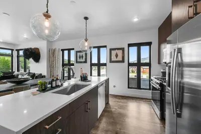 a kitchen with a sink and a refrigerator at 4-Season Modern Mountain Penthouse with Private Hot Tub & Scenic Views in Silverthorne