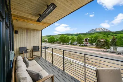 a balcony with a couch and a view of a road at 4-Season Modern Mountain Penthouse with Private Hot Tub & Scenic Views in Silverthorne