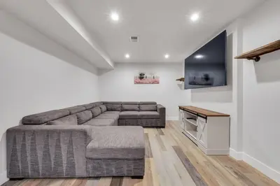 a living room with a couch and a flat screen tv at Cozy King suite- play room- hot tub in Denver