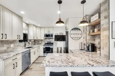 a kitchen with white cabinets and a marble counter top at Cozy King suite- play room- hot tub in Denver