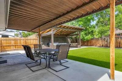 a patio with a table and chairs under a wooden pergola at Cozy King suite- play room- hot tub in Denver