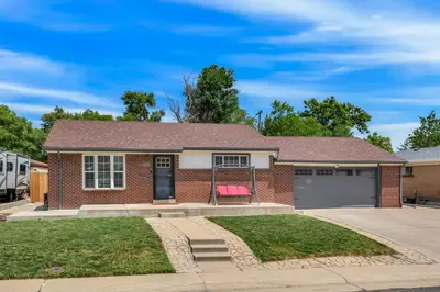 a brick house with a pink chair in the driveway at Cozy King suite- play room- hot tub in Denver