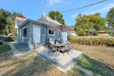 a blue house with a table and chairs and an umbrella at Longmont 2BD Comfort | Outdoor dining + Parking in Longmont