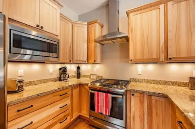 a kitchen with wooden cabinets and a stove top oven at Winter Park Getaway 4 BR Townhouse w Hot Tub in Fraser