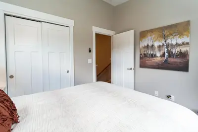 a bedroom with a white bed and a painting on the wall at 4BR Fraser Getaway Hot Tub Sleeps 10 in Fraser
