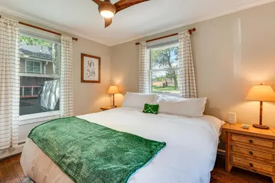 a bedroom with a large bed and two windows at Private Hot Tub - Riverfront Cabin In Estes Park! in Estes Park