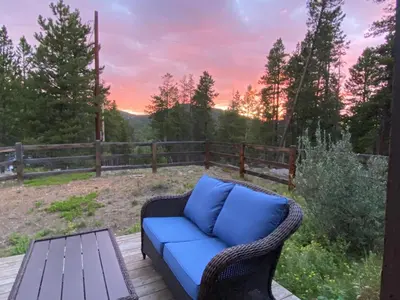 a blue couch sitting on a deck with a table at Echo Hills Mountain Lodge - Evergreen Mountain Top Retreat - Foothills of the Rockies in Evergreen