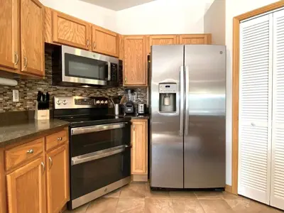 a stainless steel refrigerator in a kitchen with wooden cabinets at Echo Hills Mountain Lodge - Evergreen Mountain Top Retreat - Foothills of the Rockies in Evergreen