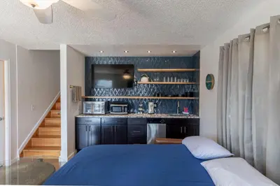 a bedroom with a blue bed and a kitchen at Modern Getaway with Private Balcony in Denver