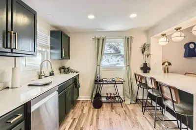 a kitchen with a sink and a counter with chairs at The Denver Duo Two Homes, One Epic Stay in Denver