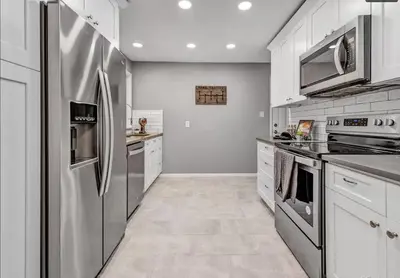 a kitchen with stainless steel appliances and white cabinets at Cozy Hot Tub Escape - Pool Table & Home Theater in Arvada