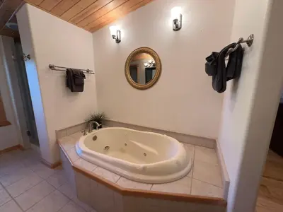 a bath tub in a bathroom with a mirror at The Carriage House, Walk to River & Lake, In Town in Grand Lake