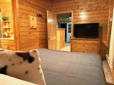 a bedroom with a bed and a flat screen tv at The Red Bears Den, Walk to River & Lake, In Town in Grand Lake