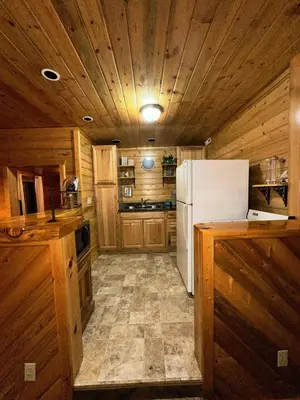 a kitchen with wooden walls and a white refrigerator at The Red Bears Den, Walk to River & Lake, In Town in Grand Lake