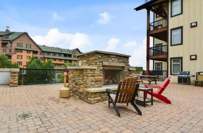 a patio with two chairs and a stone fireplace at Winter Park Village Homebase in Winter Park