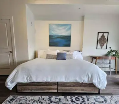 a bedroom with a large white bed with a rug at Lux Living in Cherry Creek Rooftop Pool Parking in Denver
