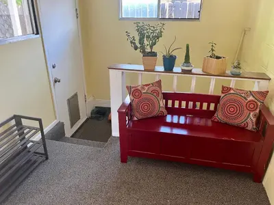 a red bench with pillows sitting in a room at Historic Home with Farm Fresh Eggs in Denver in Denver
