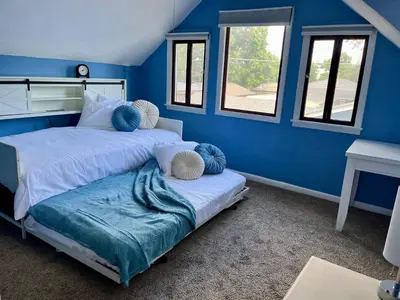 two beds in a room with blue walls and windows at Historic Home with Farm Fresh Eggs in Denver in Denver