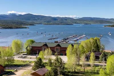 a resort on a lake with boats in the water at Beacon Landing Condo, Lakefront on Lake Granby, Luxurious Quality with Marina Right Outside in Grand Lake