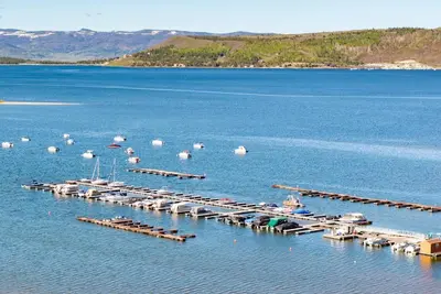 a group of boats parked in a dock in the water at Beacon Landing Condo, Lakefront on Lake Granby, Luxurious Quality with Marina Right Outside in Grand Lake