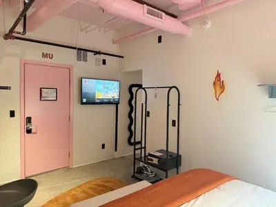 a bedroom with a pink door and a tv on the wall at BIG little Hotel in Denver