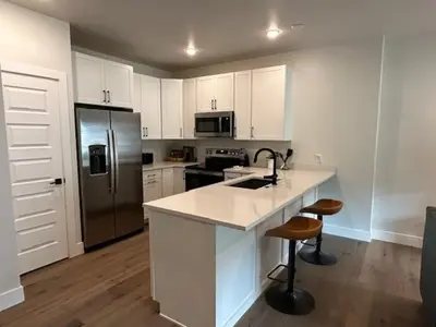 a kitchen with white cabinets and a stainless steel refrigerator at Luxury Stay Meets Family Fun- Premier 1BR Retreat condo in Keystone