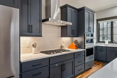 a kitchen with black cabinets and a stove top oven at Blue Horizon Chalet home in Winter Park