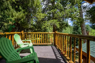 two green chairs sitting on a wooden deck at The River House home in Grand Lake