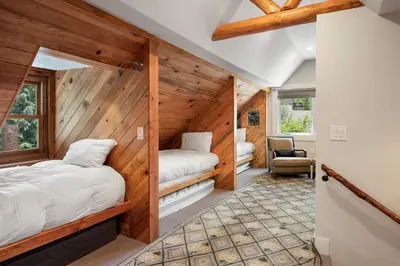 two beds in a room with wooden walls at The River House home in Grand Lake